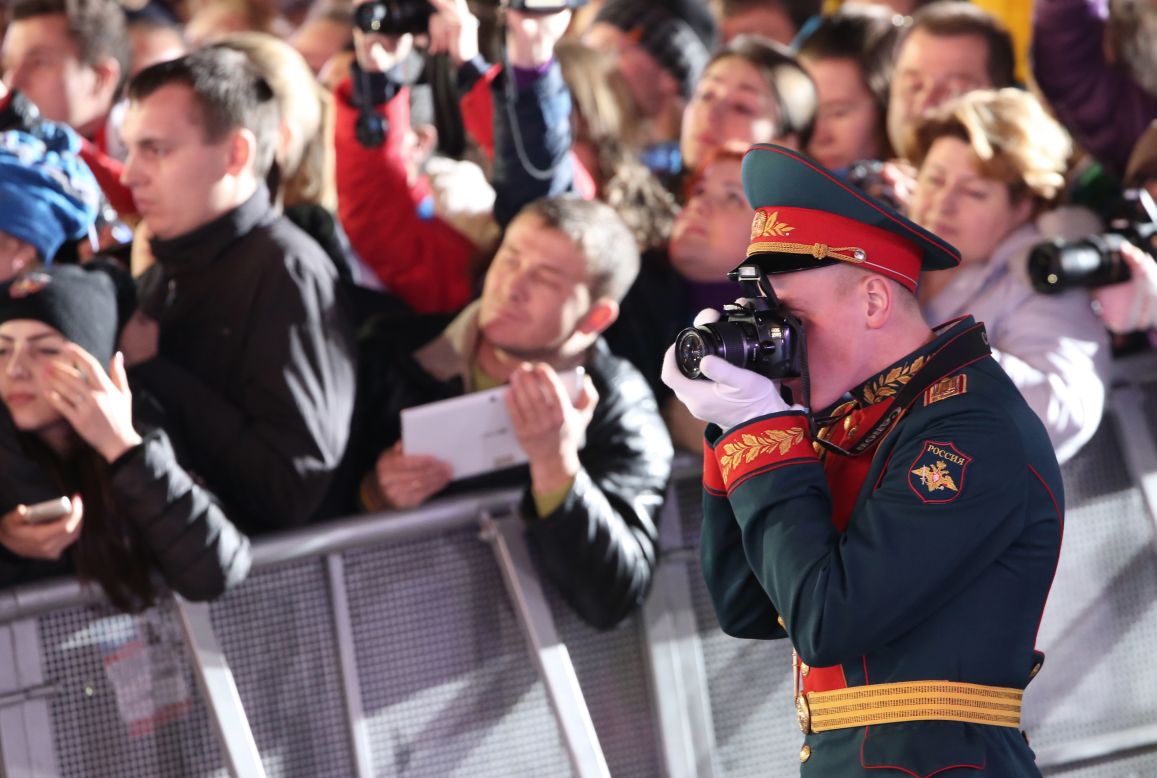 A military officer shoots pictures during the medal ceremony for team figure skating on February 10.