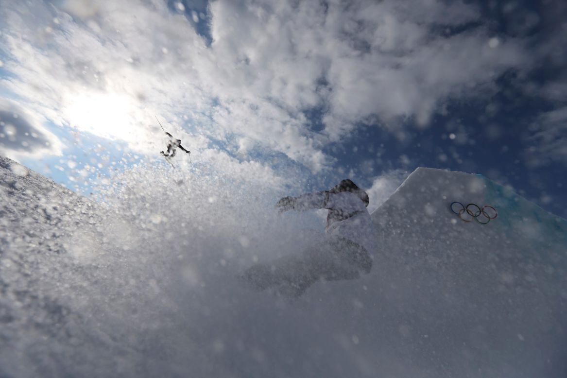 A competitor takes a jump as a team member follows during slopestyle training on February 10.