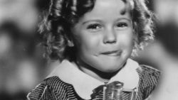 Shirley Temple (1928 - ) the American child star started performing in films at three years. She entered politics in the 60's and took on several ambassador positions representing her country. Pictured enjoying a soft drink with an impish grin on her face. (Photo by Hulton Archive/Getty Images)
