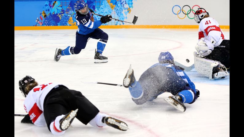 Riikka Valila of Finland takes a shot against Florence Schelling of Switzerland while teammates crash on the ice during a women's hockey game February 12.