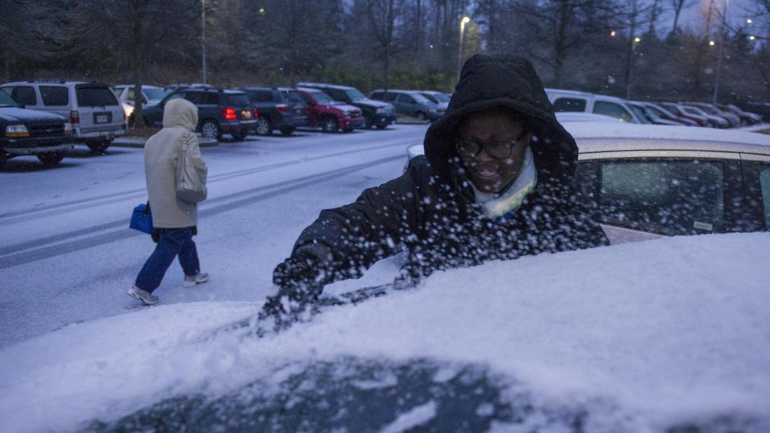 Shmetrice Moore, a nurse at an Emory University hospital in Johns Creek, Georgia, scrapes snow and ice off her windshield as she and others are released early from their shift on February 12.