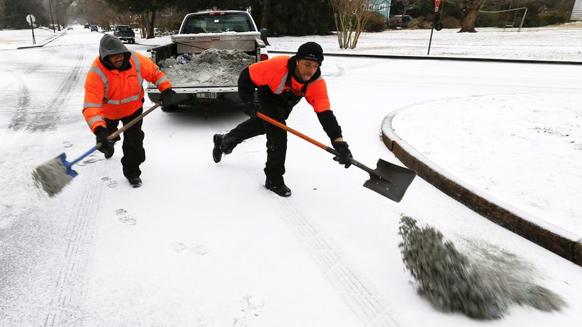 City public works employees spread a mixture of sand and salt on an intersection in Avondale Estates, Georgia, on Wednesday, February 12.