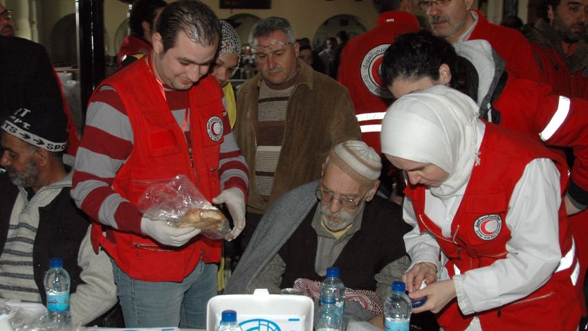 Syrians receive food and medical aid from Syrian Red Crescent workers upon their arrival in regime-held areas of the Syrian city of Homs on February 7, 2014,