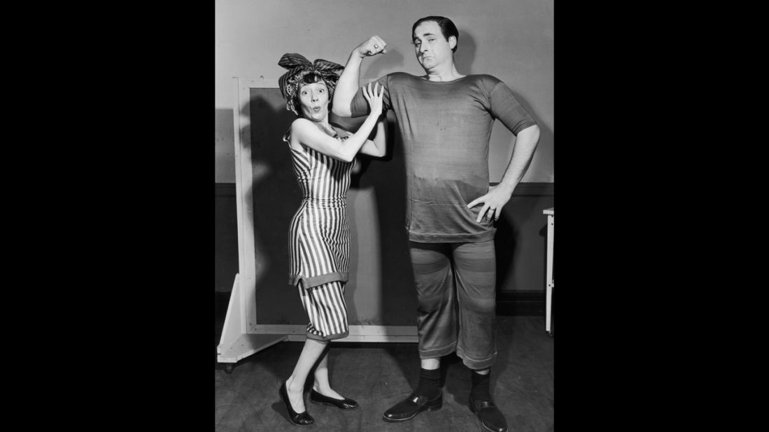 Imogene Coca feels Caesar's biceps as he mockingly flexes circa 1955. They are both dressed in period bathing suits.