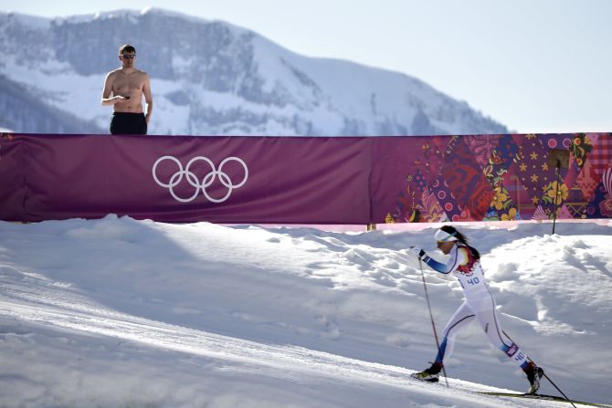 A shirtless spectator watches Swedish cross-country skier Charlotte Kalla compete during the women's 10-kilometer classic on February 13.