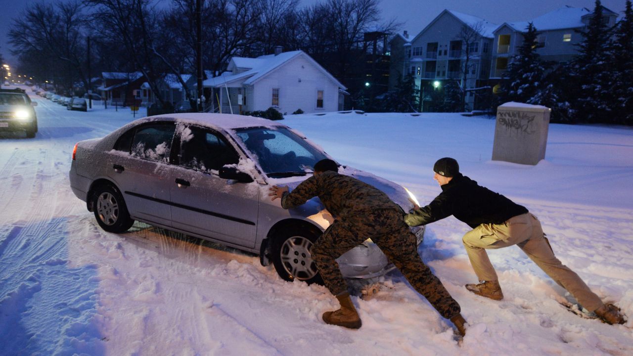 People help push a car stuck in the snow February 13 in Alexandria, Virginia.