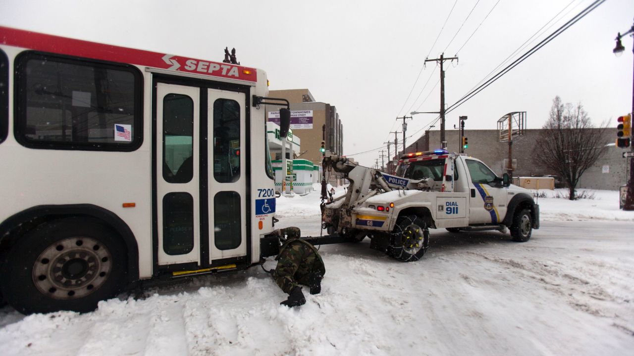 Police work to tow a bus that slid off the road in Philadelphia on February 13.