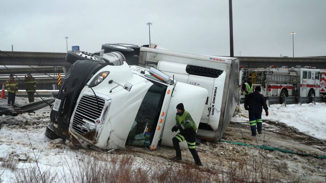 Rescue workers in Oxon Hill, Maryland, attempt to upright an overturned tractor-trailer on Interstate 495 on February 13.