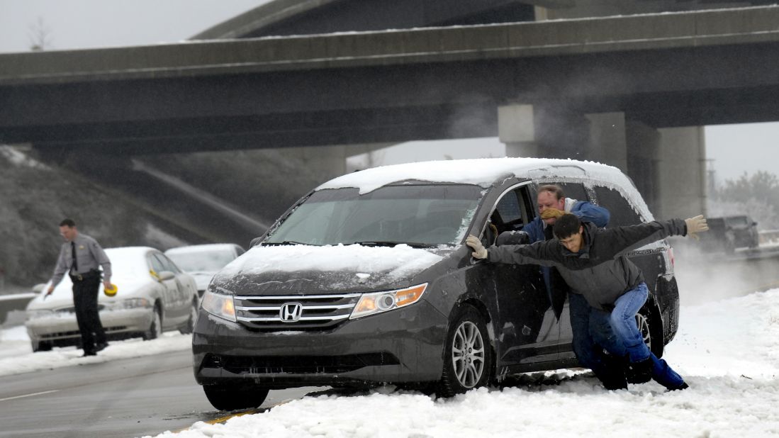 Motorists push a vehicle on Highway 70 in Raleigh, North Carolina, on February 13, a day after the worst of the storm struck the town.