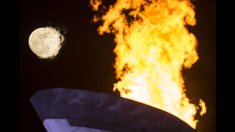 The Olympic flame burns under a full moon on February 13. 