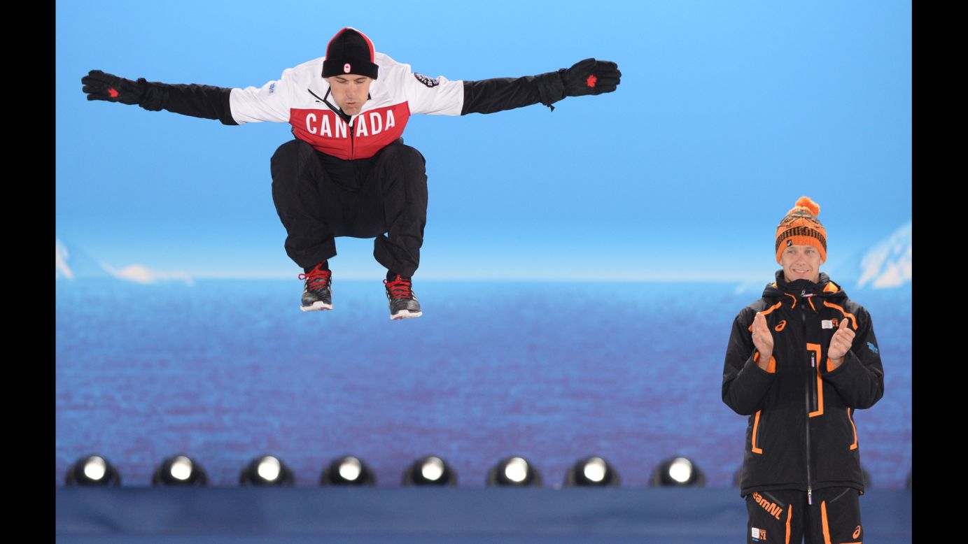 Canadian silver medalist Denny Morrison jumps next to Dutch gold medalist Stefan Groothuis during the medal ceremony for the men's 1,000-meter speedskating event.
