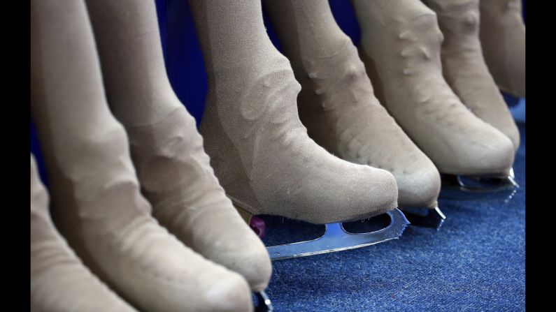 The "flower girls," charged with cleaning the ice of flowers and other trinkets thrown by fans, sit off-rink at a figure skating competition February 13.