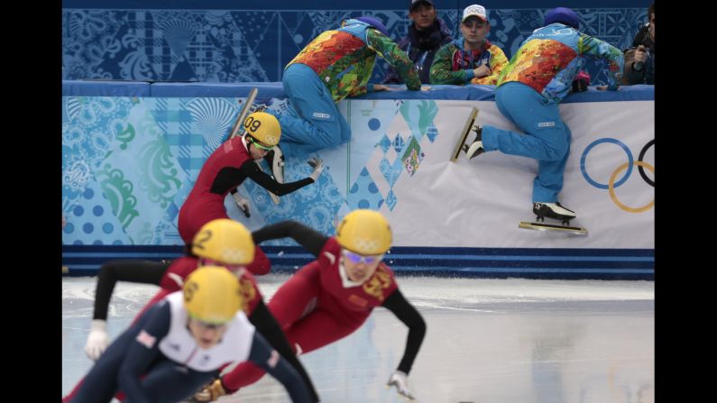 Track wardens attempt to clear the way as Fan Kexin of China crashes in the semifinals of the women's 500-meter short track speedskating competition on February 13.