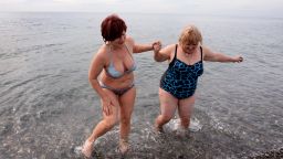 Two women enjoy the warm weather at a beach on the Black Sea near the Olympic Park in Sochi on February 14, 2014.