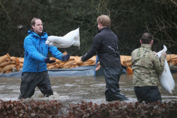 The princes toss sandbags to each other as they help with flood defense efforts February 14.