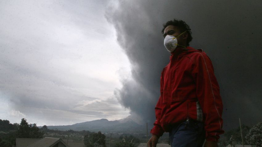 A resident evacuates under a massive plume of hot ash clouds spewing from Mount Kelud volcano as seen from Malang district in East Java province on February 14, 2014.