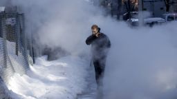 A pedestrian walks through a cloud of steam on a snowy street in New York, Friday, Feb. 14, 2014. Commuters faced slick roads on Friday after yet another winter storm brought snow and ice to the East Coast, leaving at least 24 people dead. (AP Photo/Seth Wenig)