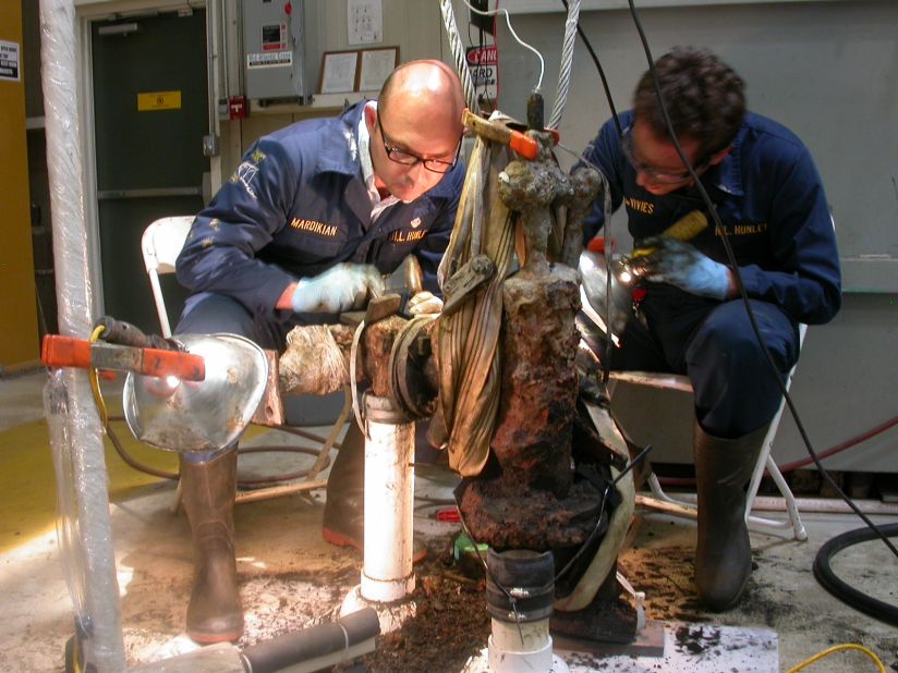 Paul Mardikian, left, senior conservator, and Philippe de Vivies remove material from a piece of the submarine.