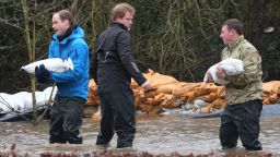 DATCHET, UNITED KINGDOM - FEBRUARY 14: Prince William, Duke of Cambridge (L) catches a sandbag thrown by his brother Prince Harry as they help soldiers build a flood defence wall at Eton End School on February 14, 2014 in Datchet, England. Flood water has remained high in some areas and high winds are causing disruption to other parts of the UK with the Met Office issuing a red weather warning. (Photo by Peter Macdiarmid/Getty Images)