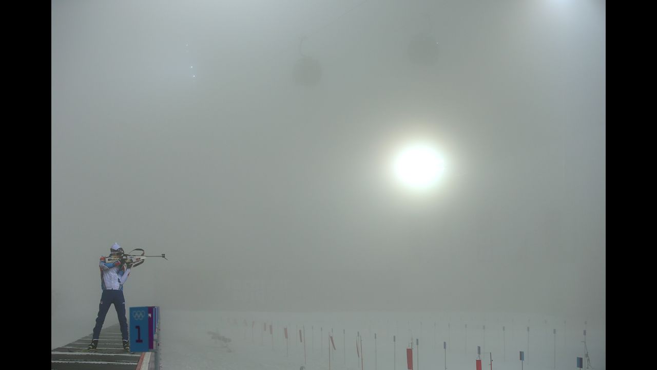 A biathlete checks the visibility through his rifle sights before the men's 15-kilometer mass start event February 16. It was postponed because of the fog.