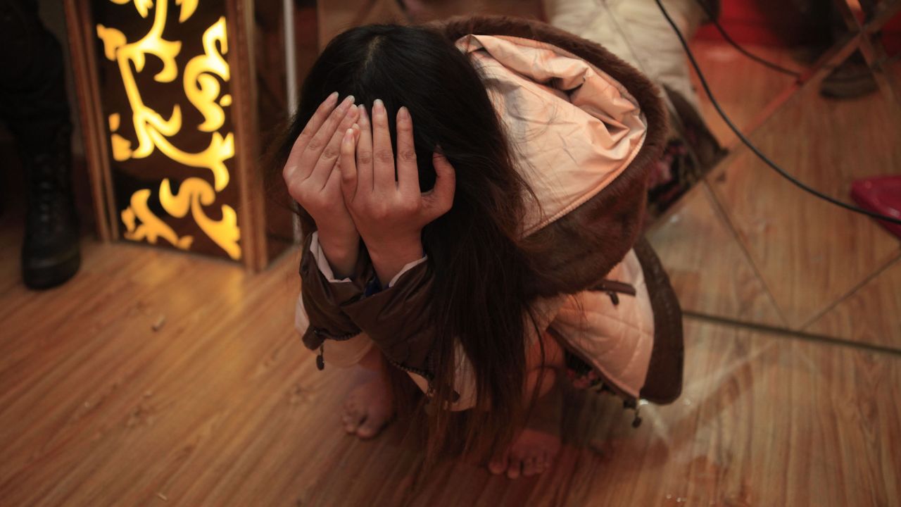 An alleged sex worker covers her face after being detained in Dongguan, China, on February 9, 2014