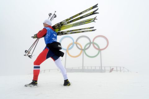 An athlete carries skis through the thick fog that caused event delays and cancellations on February 17. 