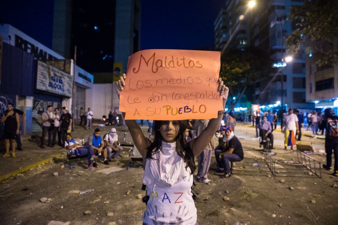 Una joven levantando un cartel frente a los efectivos de la Policía Nacional Bolivariana en la Av. Luis Roche de Altamira