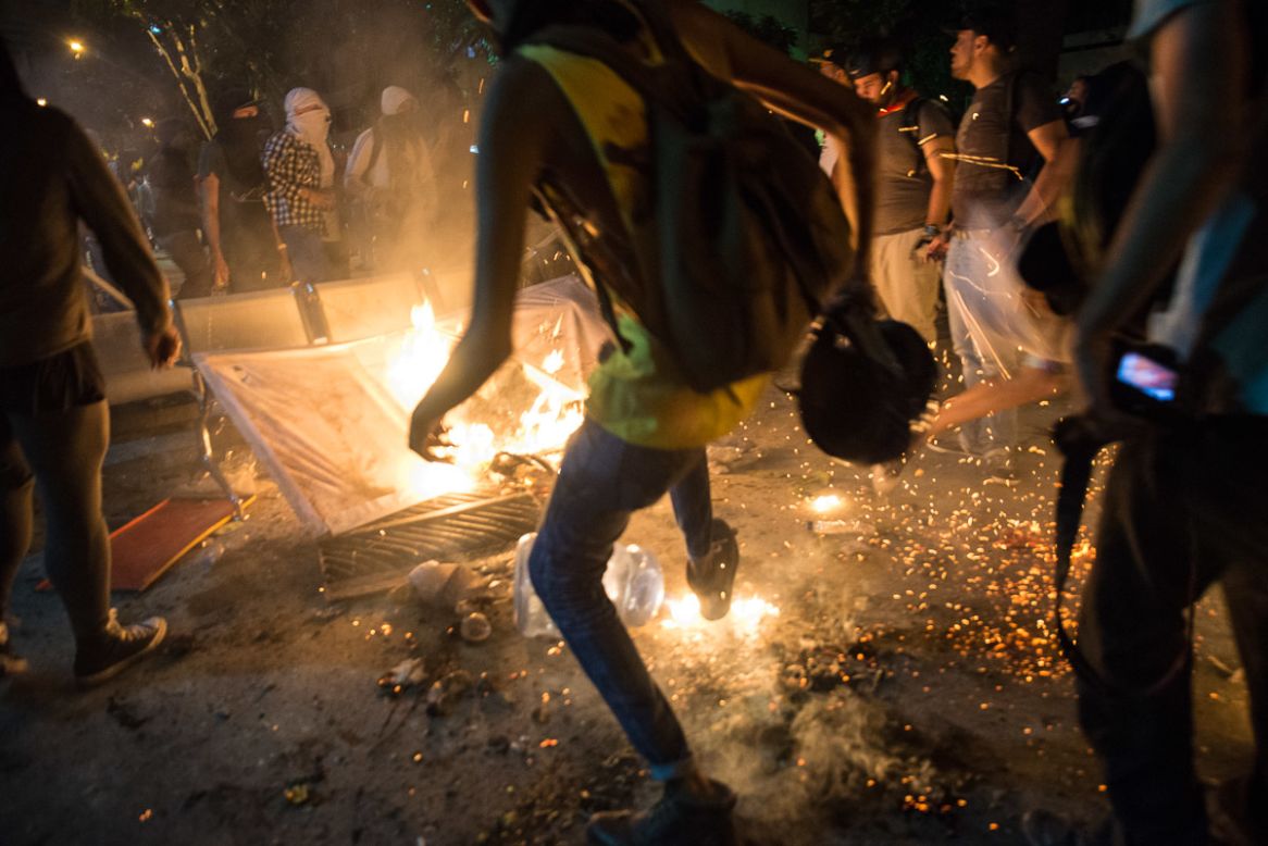 Manifestantes apagan el fuego que otros manifestantes iniciaron en la Av. Luis Roche.