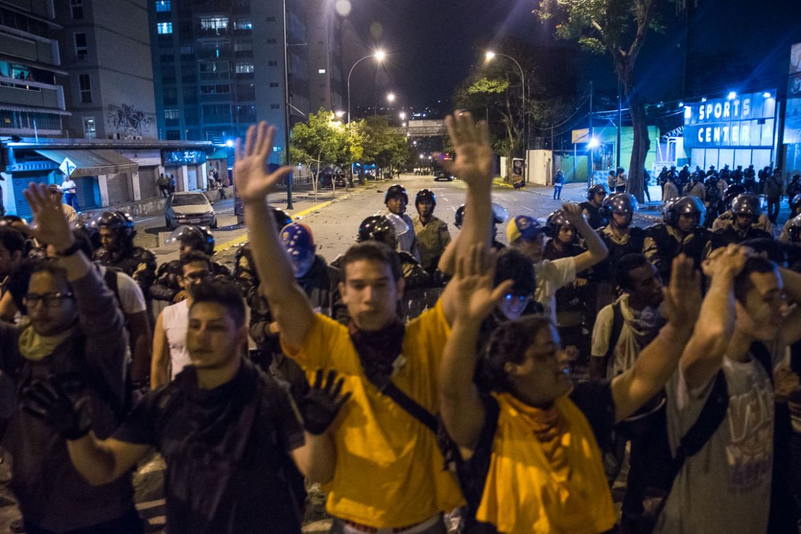 Las manos alzadas de los manifestantes pidiendo que cesen las manifestaciones violentas.