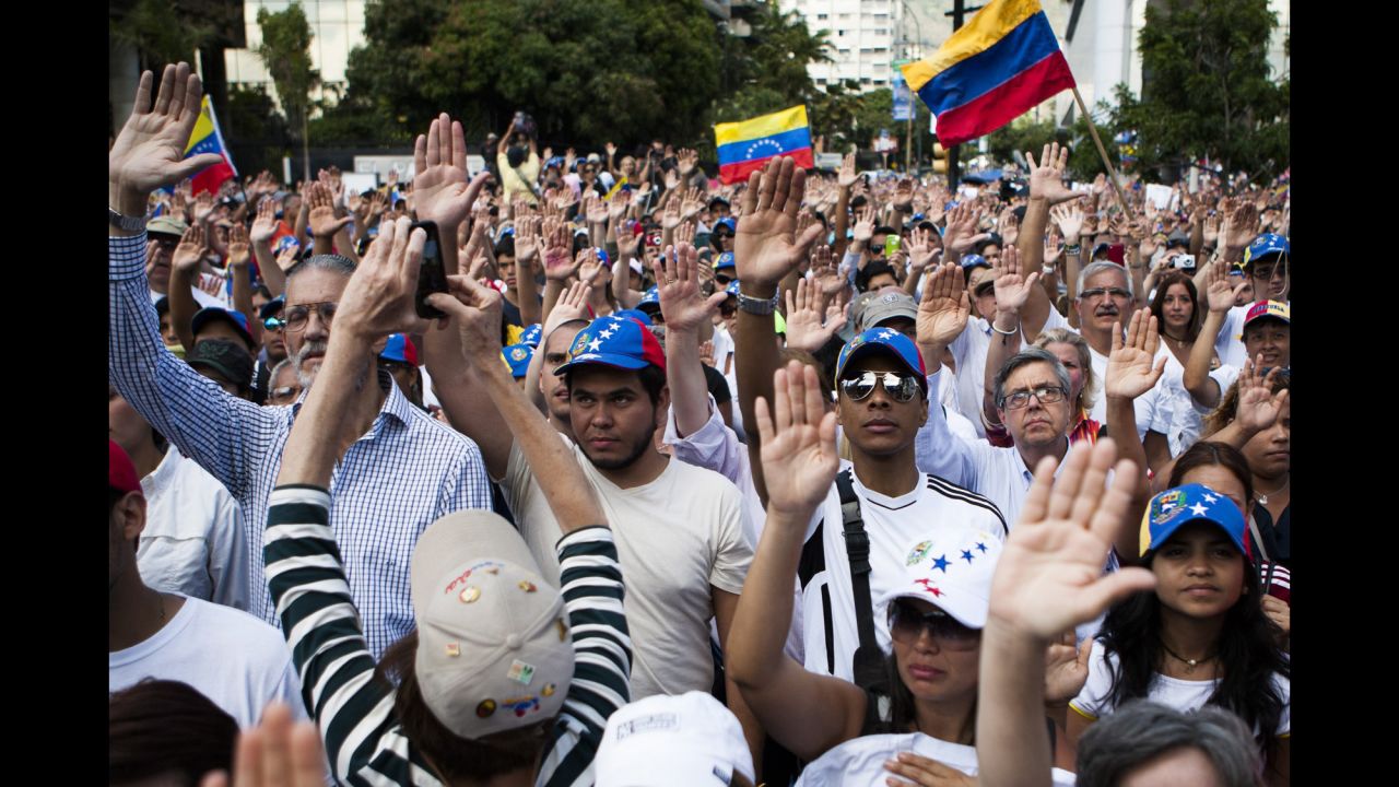 A group of protesters raise their hands during a demonstration in Caracas on Sunday, February 16. The country has an inflation rate of 56.2%, the highest in the world, and many basic goods are missing from store shelves.
