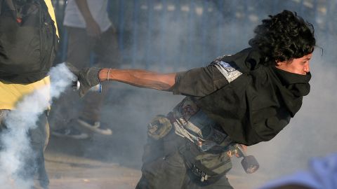 A student protester returns a tear gas canister to riot police on February 15 in Caracas.