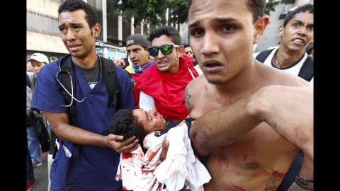 The body of a protester is carried away after gunshots were fired during an anti-government rally in Caracas on February 12.