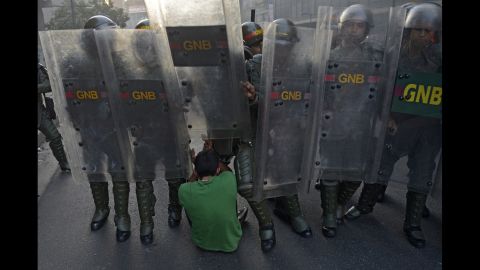 A student falls to the ground in front of riot police in Caracas on February 12.