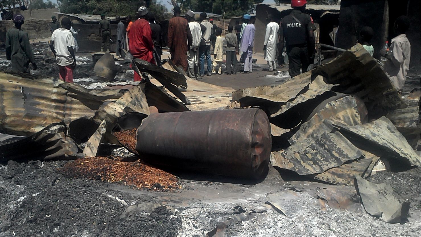 Police officers stand guard in front of the burnt-out remains of buildings in the village of Konduga, Nigeria, on February 12, 2014.