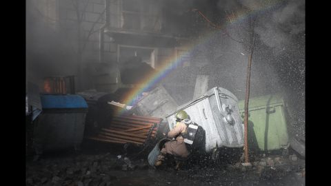 A rainbow forms over a protester ducking for cover in Kiev on February 18.