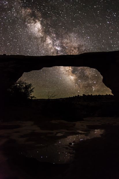 <strong>Natural Bridges National Monument (Utah): </strong>The natural Owachomo Bridge in Utah is silhouetted against the Milky Way and thousands of stars. This photo was taken on a particularly clear night after a storm, and features potholes full of water reflecting the scene, says photographer <a href="http://jwfrank.com" target="_blank" target="_blank">Jacob Frank</a>. 