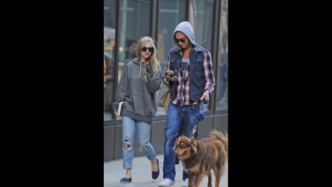 Actress Amanda Seyfried, left, wears shredded jeans and an oversized sweatshirt while walking her dog through Washington Square Park in New York City. 