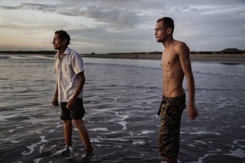 A father and son who are both sick with kidney disease wade in the water at the beach in Puerto Corinto, a coastal town near Chichigalpa.
