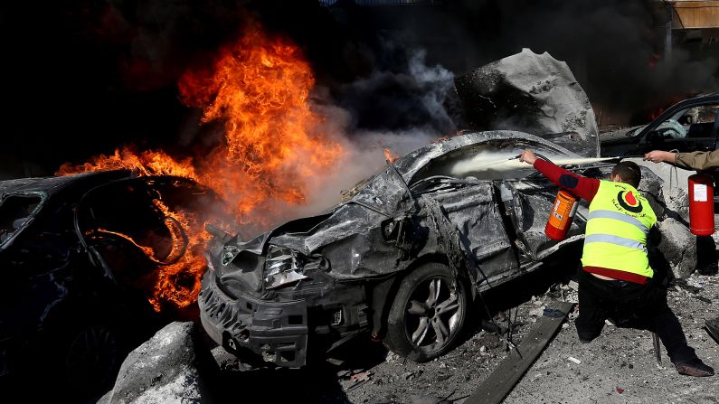 A civil defense worker tries to extinguish flames from a car in Beirut on February 19.