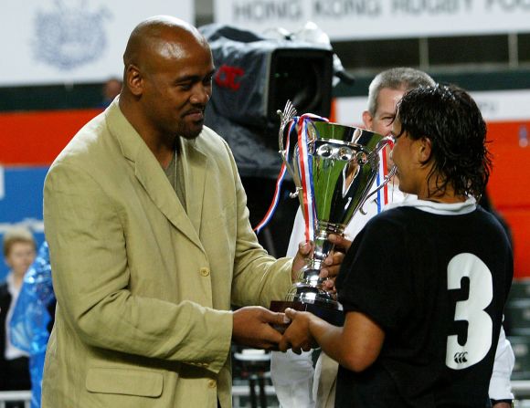 Lomu's last international match was in late 2002, but after his kidney transplant he played club rugby sporadically until 2010. Here Lomu presents Annie Brown of New Zealand with the Women's Rugby Sevens trophy during the 2004 Hong Kong Sevens.