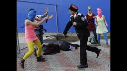 A Cossack militiaman attacks Nadezhda Tolokonnikova and a photographer as she and fellow members of the punk group Pussy Riot, including Maria Alekhina, right, in the pink balaclava, stage a protest performance in Sochi, Russia, on Wednesday, Feb. 19, 2014. The group had gathered in a downtown Sochi restaurant, about 30km (21miles) from where the Winter Olympics are being held. They ran out of the restaurant wearing brightly colored clothes and ski masks and were set upon by about a dozen Cossacks, who are used by police authorities in Russia to patrol the streets. (AP Photo/Morry Gash)