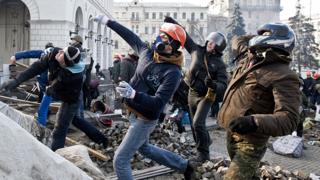 Protesters throw rocks at riot police in Independence Square on February 19.
