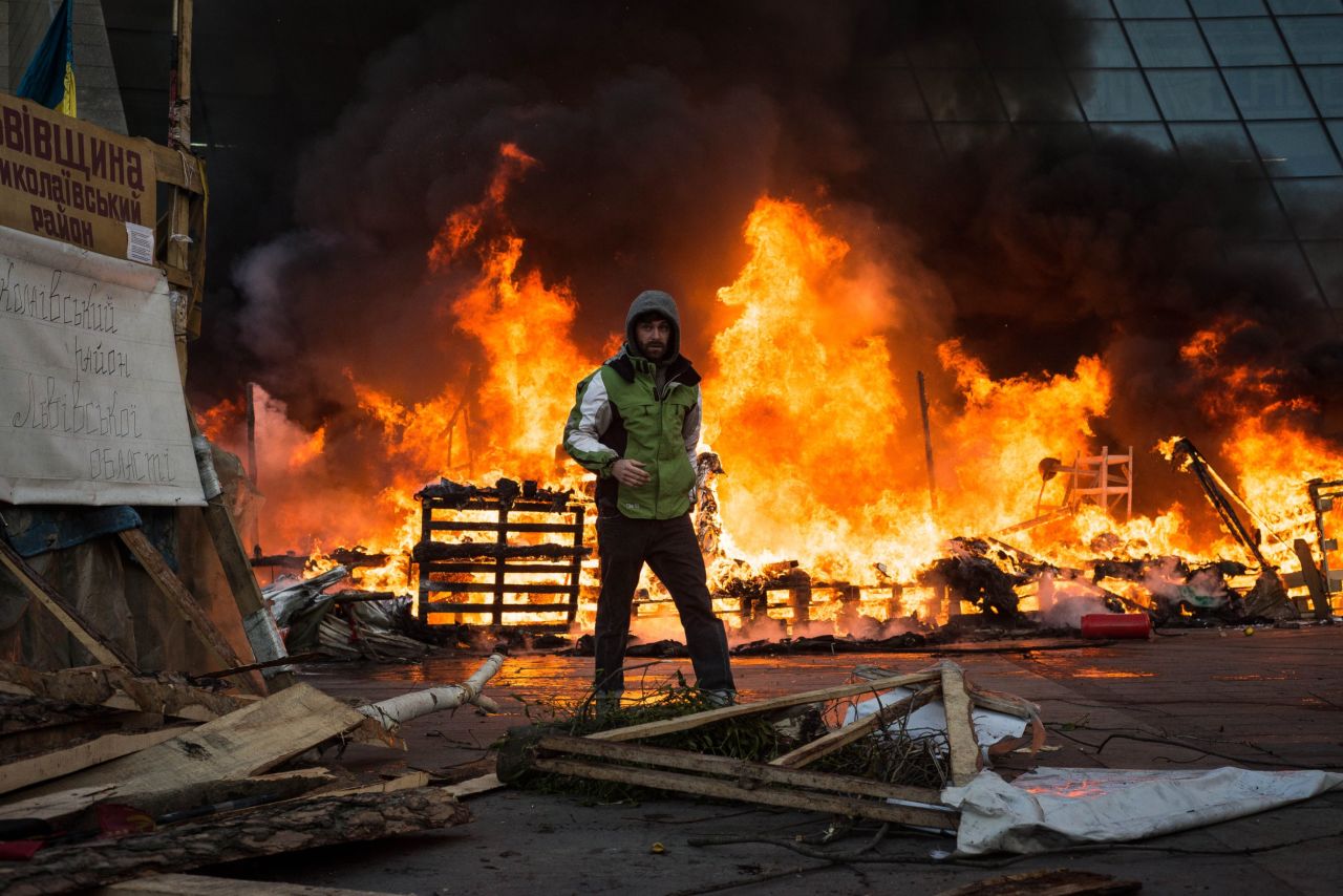 A Ukrainian protester stands in front of the burning Euromaidan protest camp in Kiev on Wednesday February 18. Protesters set up tents in the square in December, says iReporter and American journalist <a href="http://ireport.cnn.com/docs/DOC-1087484">Chris Collison</a>.