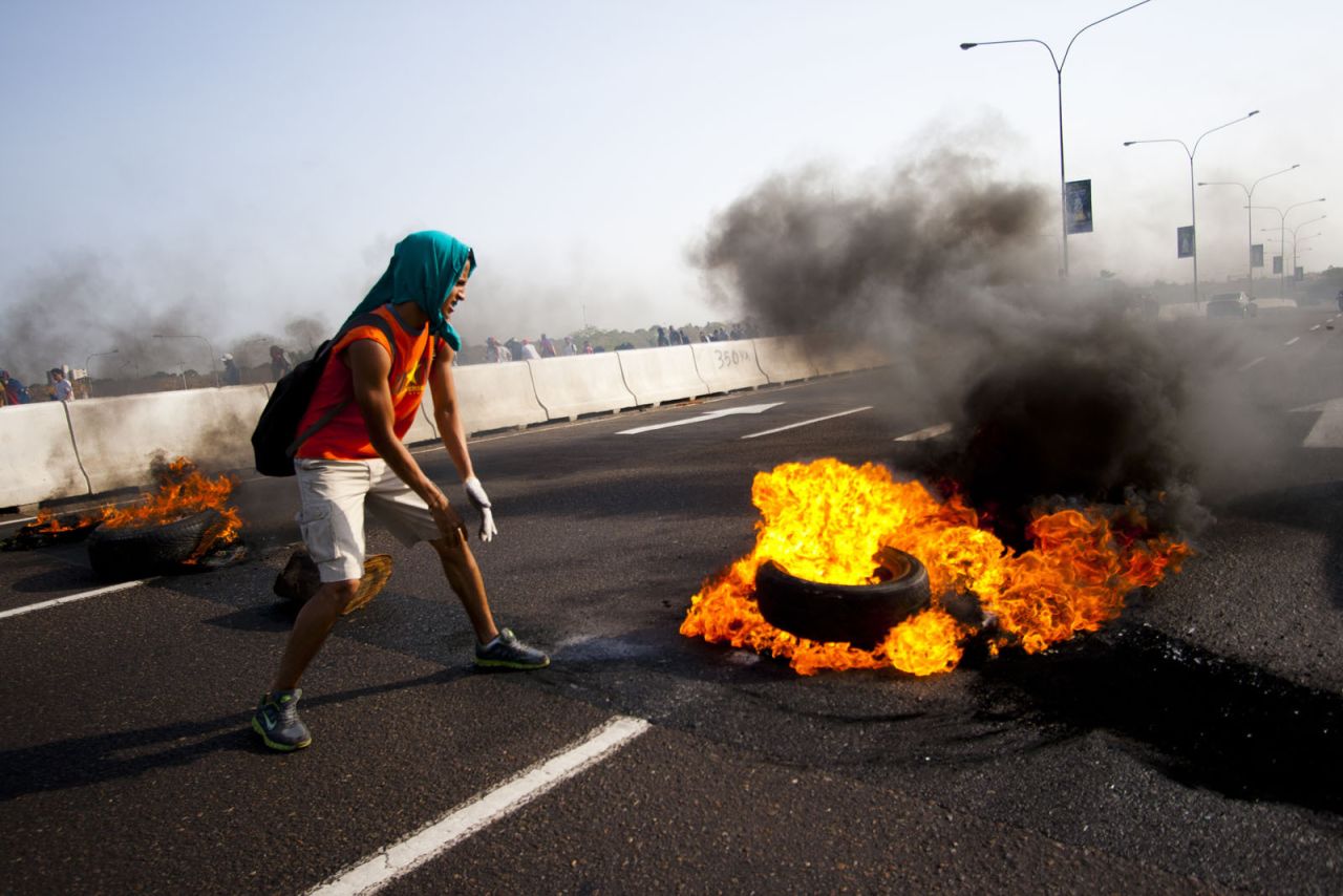 A student in Maracaibo <a href="http://ireport.cnn.com/docs/DOC-1086131">lights a tire on fire</a> on February 15. Rojas explained this is a maneuver students use to close down streets.