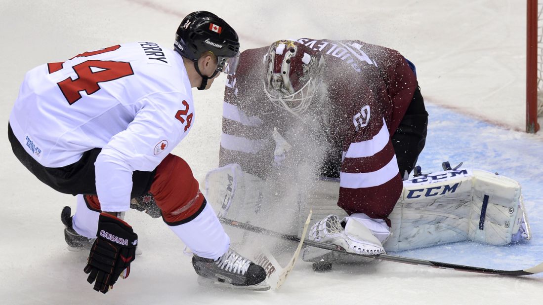 Canada's Corey Perry, left, sprays ice onto Latvia goalie Kristers Gudlevskis during their hockey game February 19.