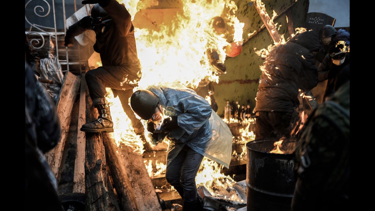 Protesters run from a burning barricade in Kiev on February 20.