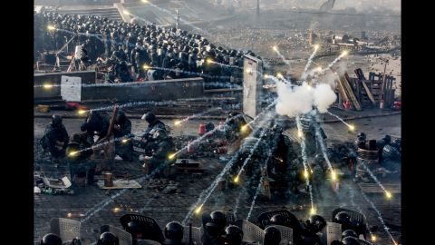 La  policía se cubre tras los escudos mientras los fuegos artificiales se apagan en Kiev el 19 de febrero.