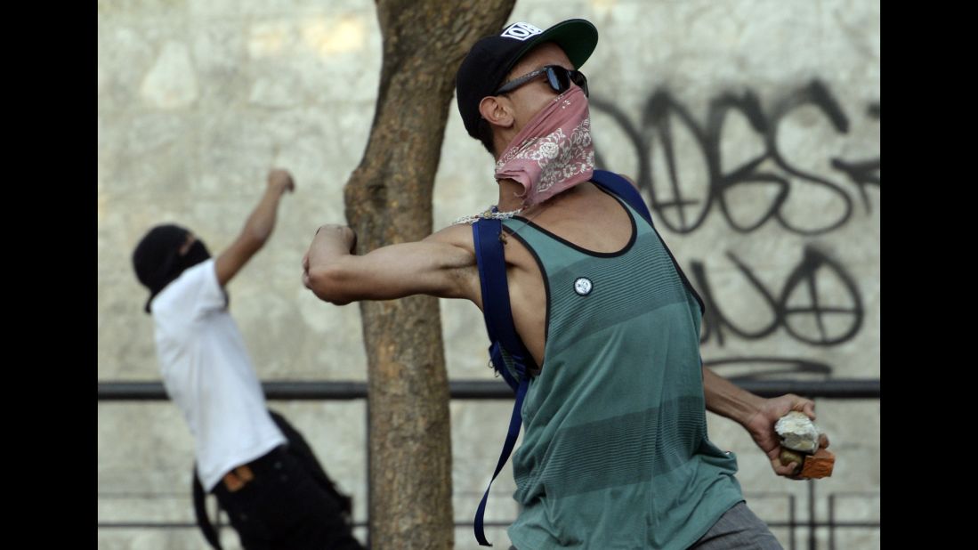 Protesters throw stones at riot police in Caracas on February 19. Protesters have been demanding better security, an end to scarcities, and protected freedom of speech.