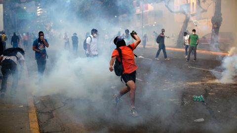 Protesters throw objects amid tear gas launched by riot police in the Altamira neighborhood of Caracas on February 19.