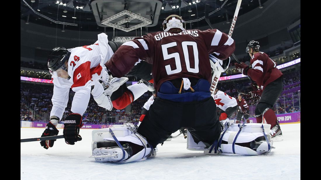 Canada forward Corey Perry trips over Latvia goaltender Kristers Gudlevskis during the men's ice hockey quarterfinal on Wednesday, February 19.